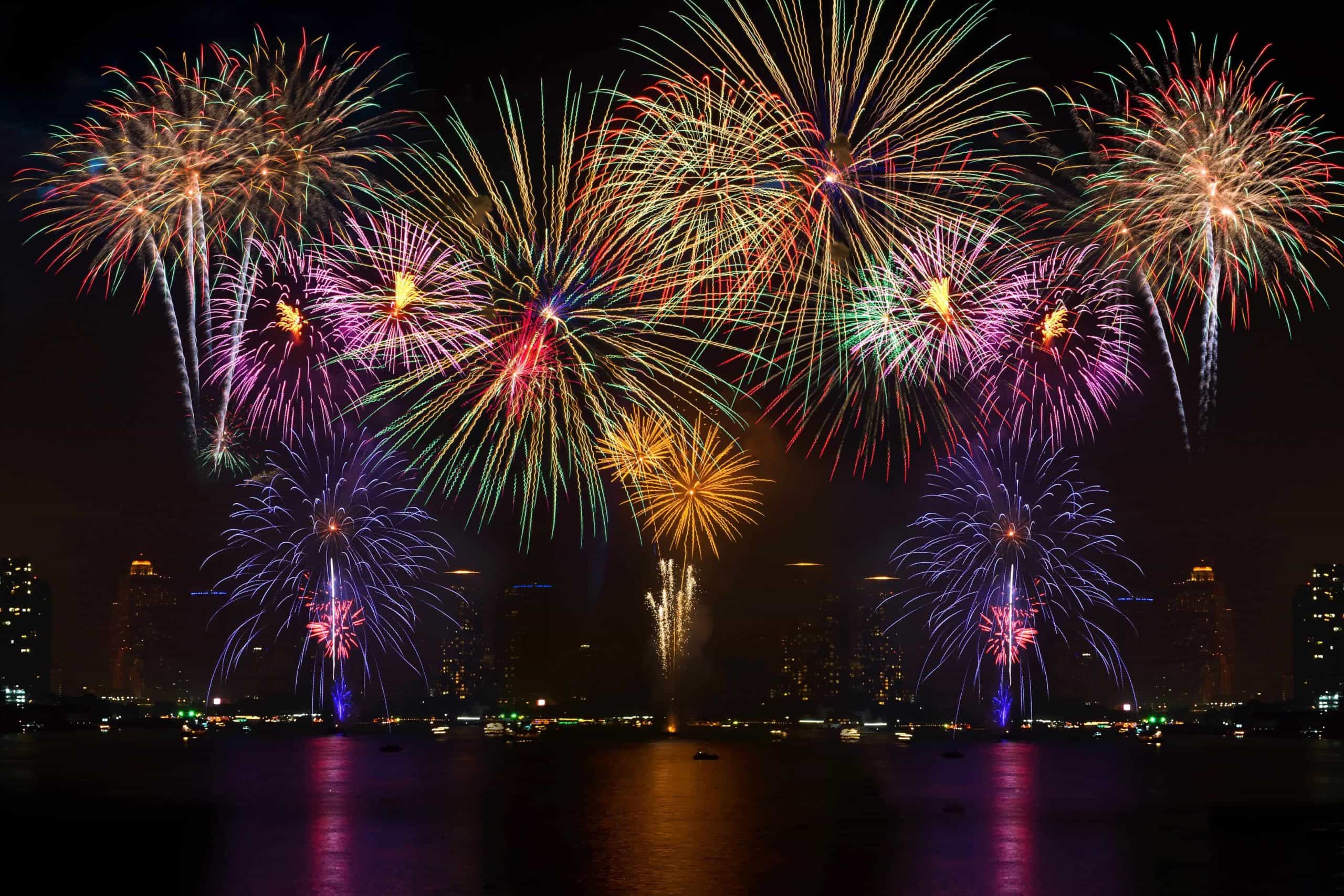 Colorful fireworks display lighting up the night sky over a city skyline and waterfront