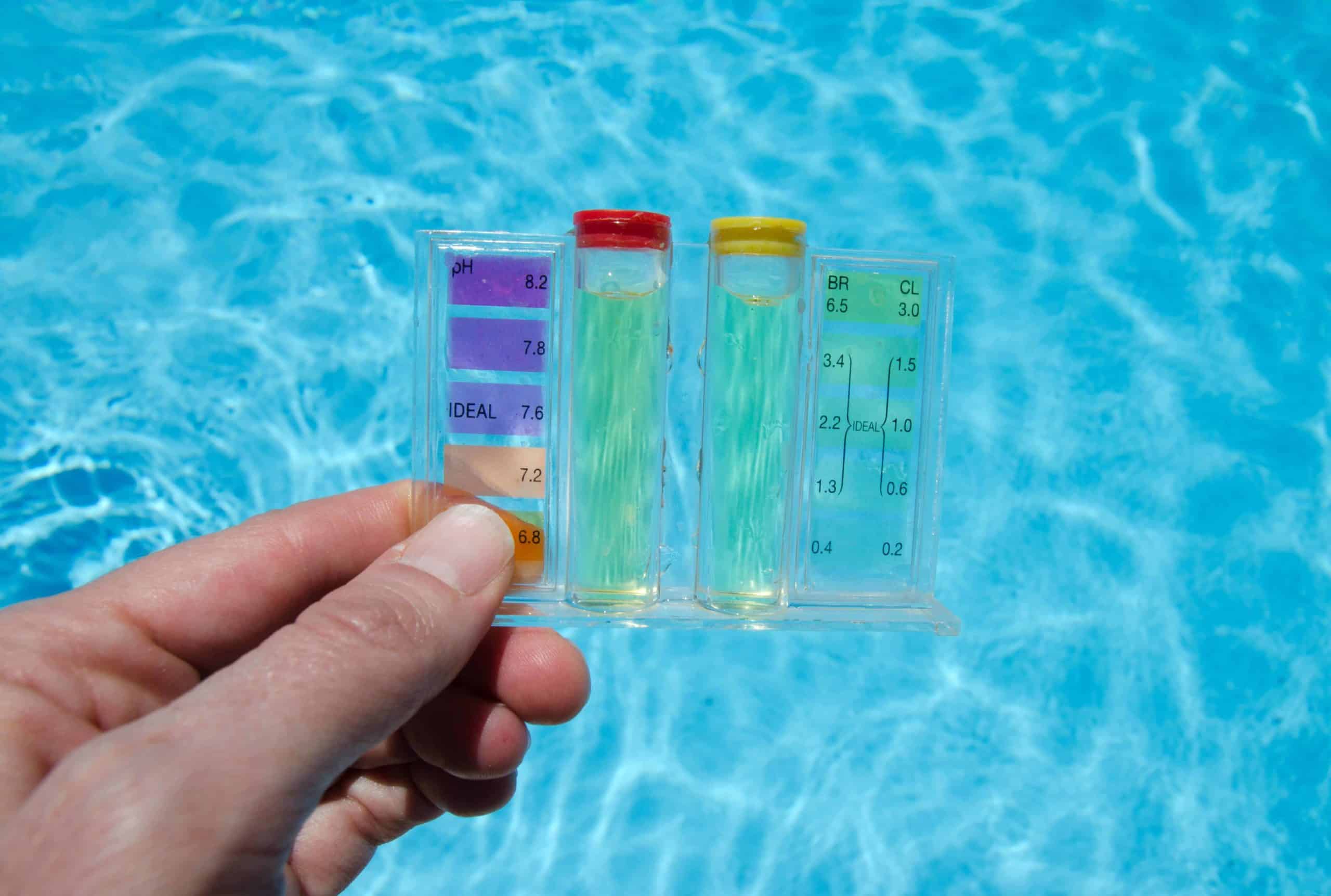 Someone holds a tool to check the water quality of a swimming pool.
