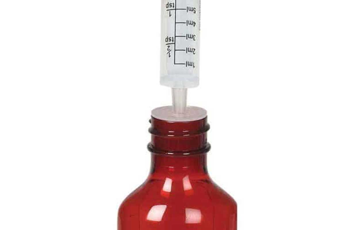A syringe is inserted in a liquid medicine bottle.