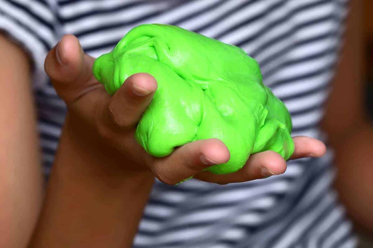 Child's hand holding a ball of bright green slime