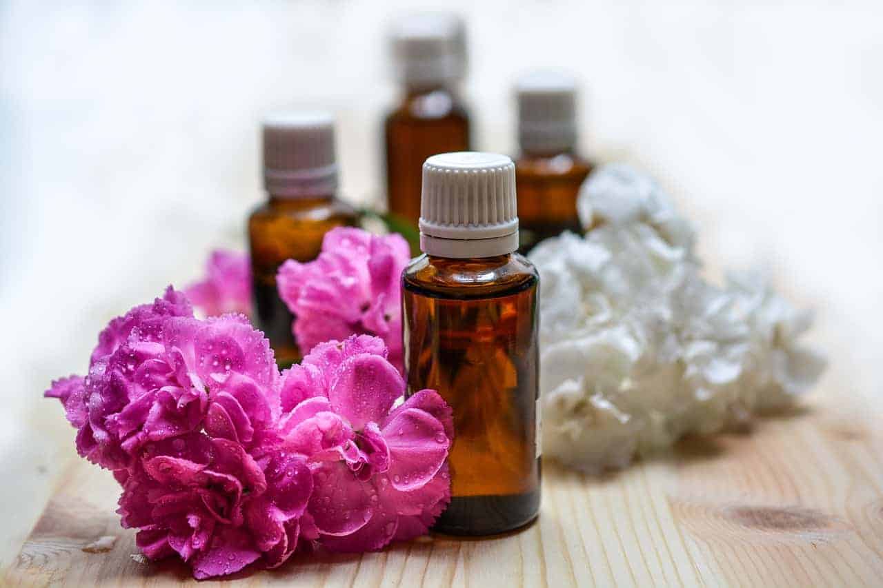 Small amber essential oil bottles surrounded by pink and white flowers