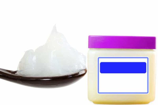 Petroleum jelly on a spoon next to a container.
