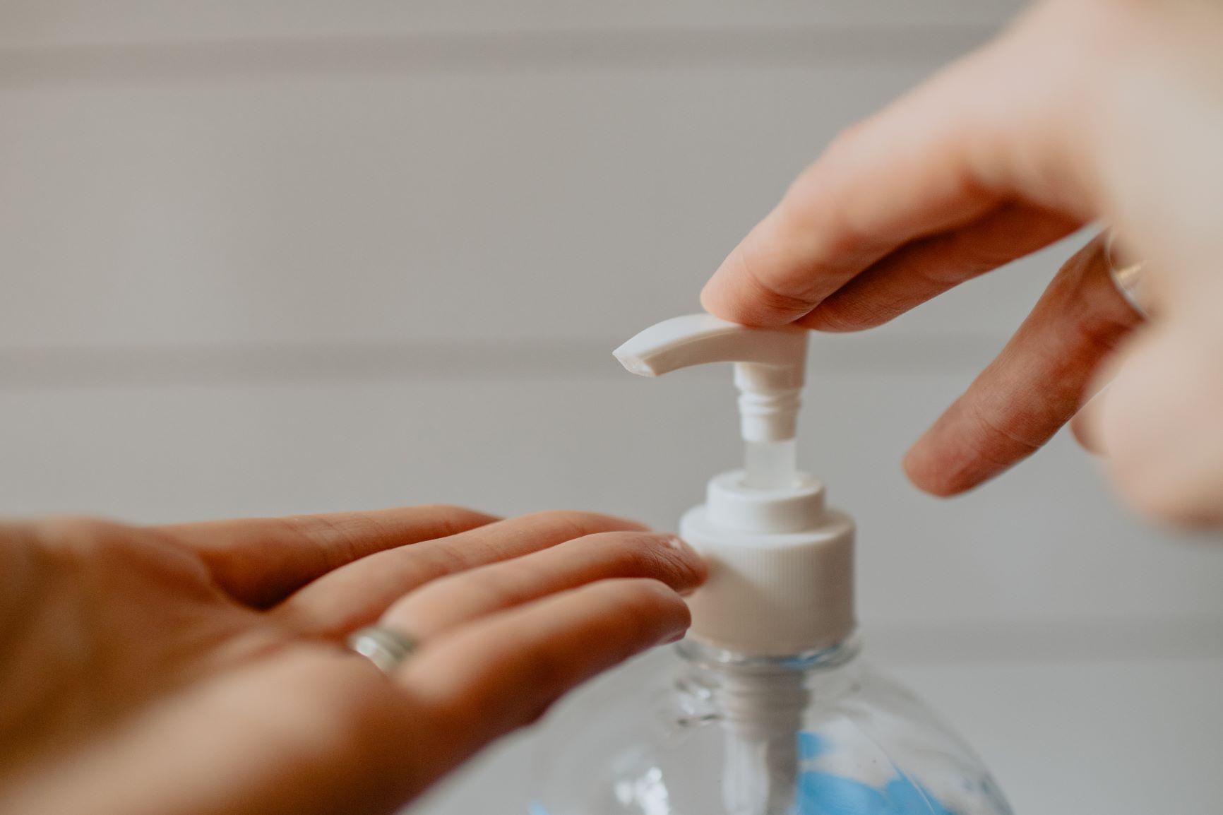A woman pumps hand sanitizer onto her outstretched hand.