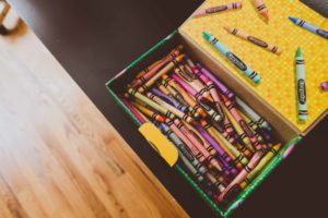 Open box of Crayola crayons on a wooden desk