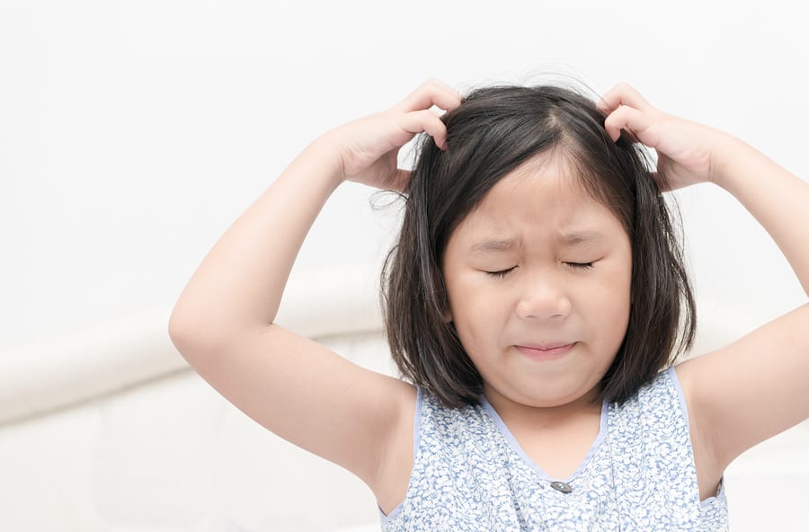 Young girl scratching her head with both hands