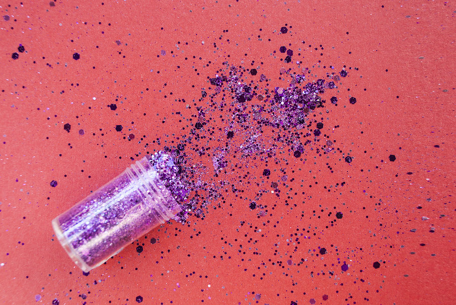 A small tube of purple glitter on a red background
