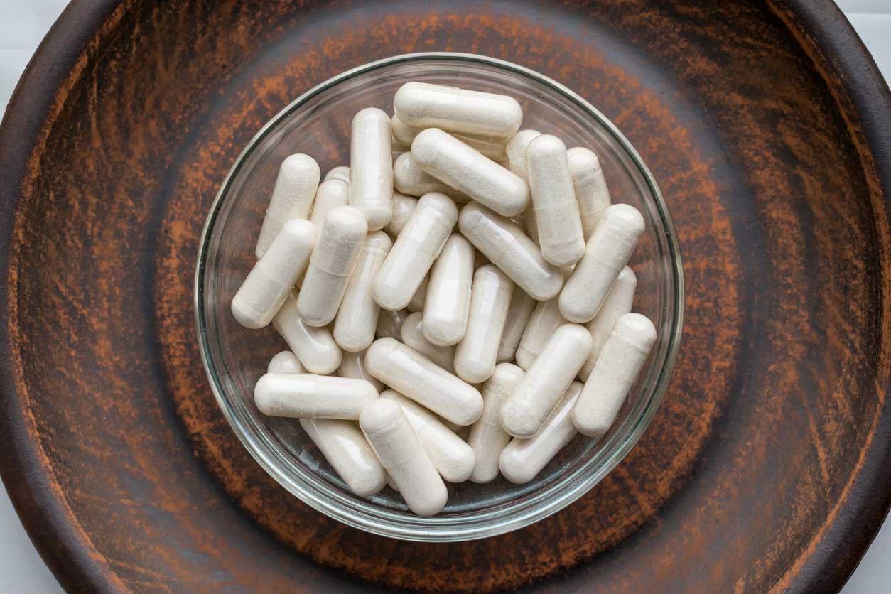 an image of kava kava capsules in a wood bowl.