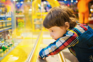 A young child leaning over a glass display case, curiously peering inside at the contents.