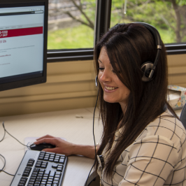 Smiling woman wearing a headset working at a computer, representing a poison center specialist