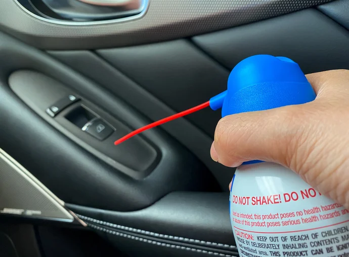 An air duster being used to clean a car interior.