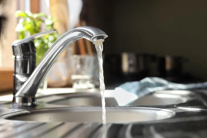 Water runs out of a kitchen faucet into the sink below.