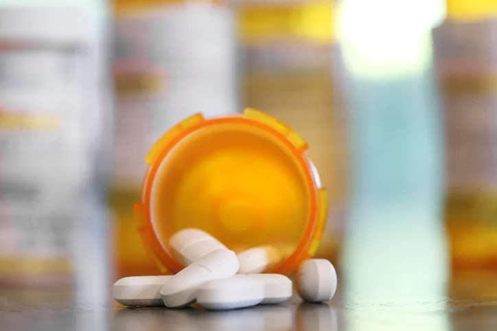 Pills spill out of an overturned prescription bottle.